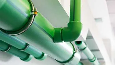 Bright green pipes, secured by metal clamps, run along a white ceiling.