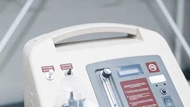 Close-up of a medical oxygen concentrator's control panel, featuring a flowmeter and two oxygen outlets.
