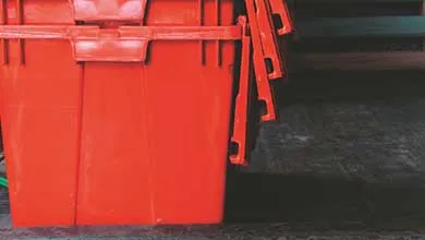 Stacked red plastic bins arranged in rows inside an industrial facility.
