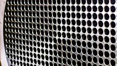 Close-up of a perforated metal grille with a grid of small circular holes, viewed at an angle.