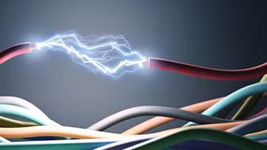 A bright blue electric arc sparks between two exposed red wires above curved, multicolored cables on a dark gray background.