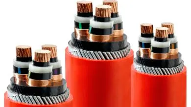 Close-up cross-section of three thick red industrial electrical cables on a white background, showing an outer red sheath, braided steel wire armor, and multiple inner copper conductors.